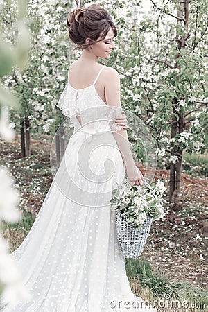 Beautiful sweet gentle happy girl in a beige boudoir dress with flowers in a basket holding , photo processing in the style of mod Stock Photo