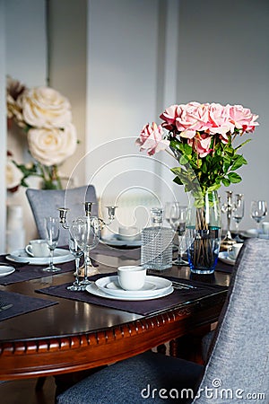 A beautiful table served with dishes and a bouquet of roses. Stock Photo