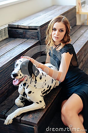 Beautiful tall girl in black dress with dog Dalmatian in studio Stock Photo