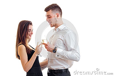 Beautiful tall guy in a white shirt standing next to an attractive girl, and they drink champagne from glasses Stock Photo