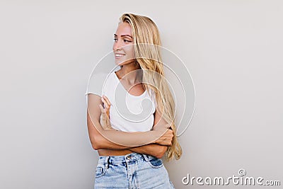 Beautiful tanned girl with long hairstyle looking away. Sensual cheerful woman smiling on white bac Stock Photo