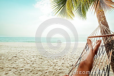 Beautiful Tanned legs of women. relax on hammock at sandy tropical beach Stock Photo