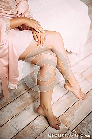 Beautiful tanned slim legs of young woman wearing pink dressing gown Stock Photo