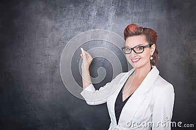 Beautiful teacher with piece of chalk on blackboard background Stock Photo