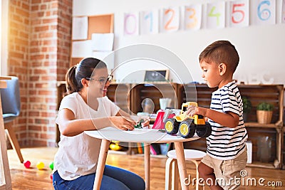 Beautiful teacher and toddler boy playing with tractor and cars at kindergarten Stock Photo