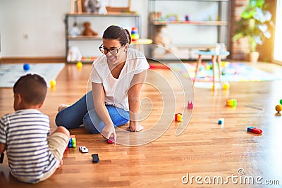 Beautiful teacher and toddler boy playing with tractor and cars at kindergarten Stock Photo