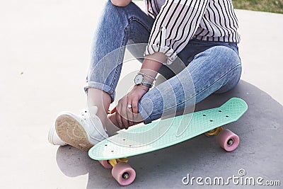 Beautiful teen female skater sitting on ramp at the skate park. Concept of summer urban activities Stock Photo