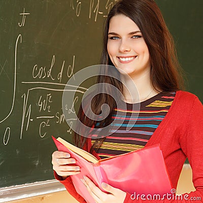 beautiful teen girl high achiever in classroom near desk with formulas of higher mathematics Stock Photo