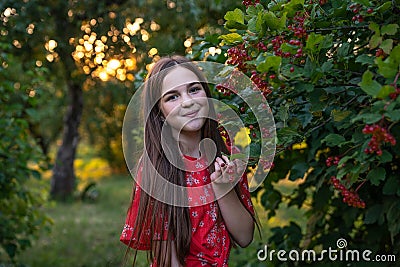 Beautiful teen girl with red hair and freckles peeping from behinde a bush of viburnum Stock Photo