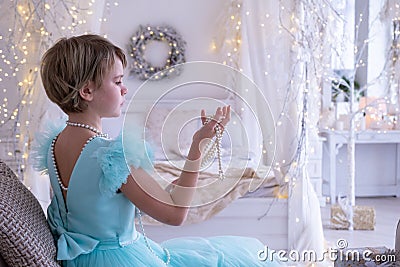 A beautiful teenage girl in a chic dress with an open back. A girl looks with interest at a Christmas present - a string Stock Photo