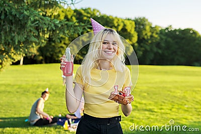 Beautiful teenage girl in a festiv hat on her birthday with a cake and candles. Stock Photo