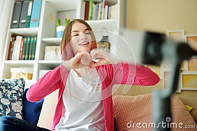 Beautiful teenage girl recording video blog with her smartphone. Young vlogger shooting vlog at home. Teen influencer creating Stock Photo