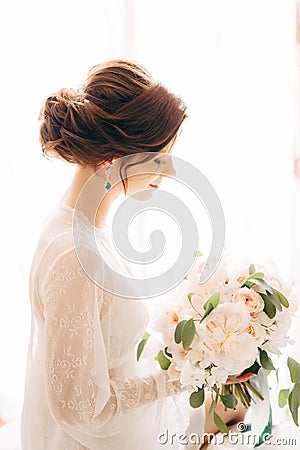 Beautiful tender bride with bridal bouquet of cream roses and eucalyptus Stock Photo