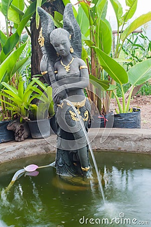 A beautiful Thai-style fairy statue standing in a pool of home g Stock Photo