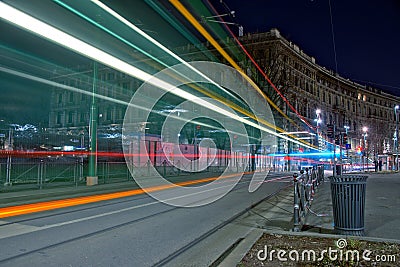 Beautiful timelapse shot of car lights on the asphalt road in front of a building at night in Milan Stock Photo