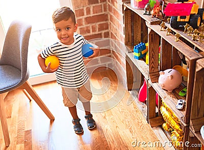 Beautiful toddler boy playing with colored small balls at kindergarten Stock Photo