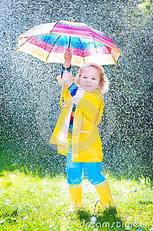 Beautiful toddler with umbrella playing in the rain Stock Photo