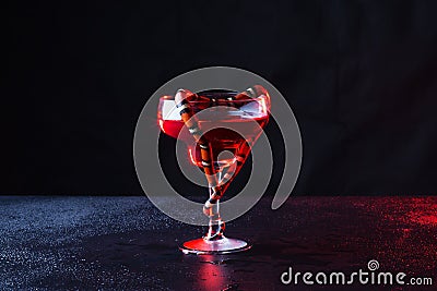 Beautiful transparent glass with red liquid and little snake which was curtailed in the form of heart against a dark background Stock Photo