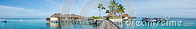 Beautiful tropical beach panorama of bungalos with bridge near the ocean with palms trees and boats at Maldives Stock Photo