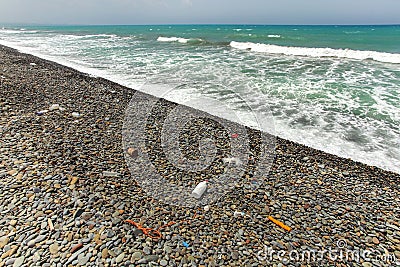 Beautiful unspoiled dark pebble stones beach with garbage, mostly plastic, washed out. Ocean littering concept Stock Photo