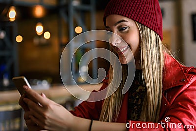 Smiling beautiful urban girl using smart-phone out in the cafeteria Stock Photo