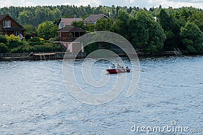 Ivanovo region, Russia, July 3, 2023. A small boat with people on the river against the backdrop of the village. Editorial Stock Photo