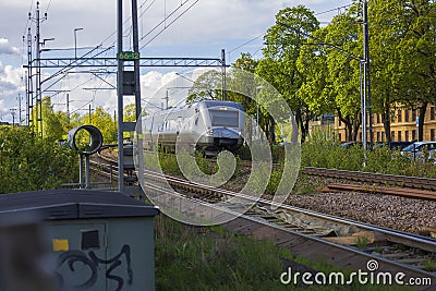 Beautiful view of coming speed electric train passing crossroad in town. Editorial Stock Photo