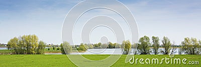 Beautiful view on a dutch landscape near the river Waal and Zaltbommel, water, green grass, meadows and trees on a sunny day Stock Photo