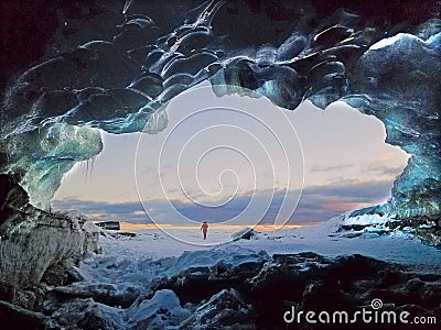 Beautiful view from a frozen cave of a person with red coat in a snowy place at sunset Stock Photo