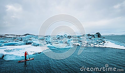 Beautiful view of icebergs glacier lagoon with a guy paddle boarding sup Stock Photo