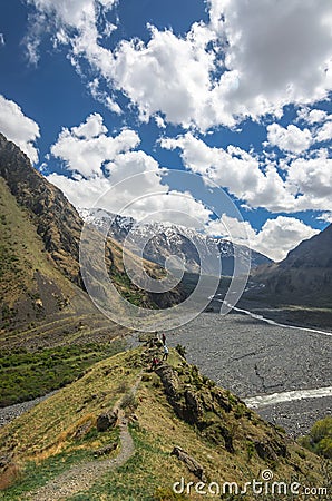 Beautiful view on impressive gorge in Caucasus mountains. Monument in form of Cross and path to it Stock Photo