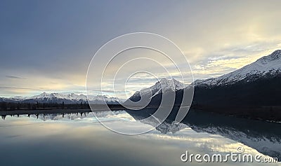 Beautiful view of a lake with the reflection of the snow-covered mountains at sunset Stock Photo