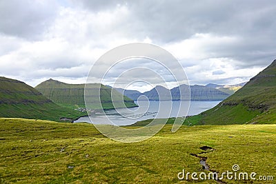 Beautiful view of a large green pasture sloping down towards the blue ocean. Stock Photo
