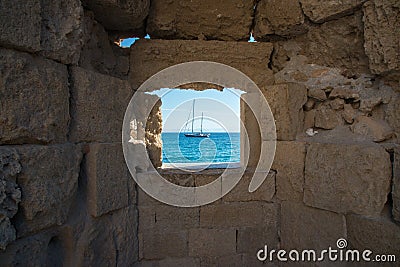 Beautiful view of mediterranean sea with a ship, framed by a window on Rhodes city walls. Greece Stock Photo