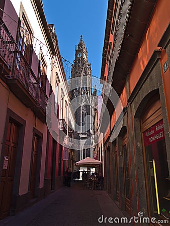 Beautiful view of narrow alley in the historic center of town Arucas, Gran Canaria, Spain with people sitting in cafe. Editorial Stock Photo