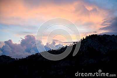 Beautiful view on sky and clouds at sunrise. Dark silhouettes of mountains at dawn. Stock Photo