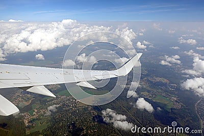 View to the earth from passenger supersonic airplane window flying high in the sky above white clouds Stock Photo