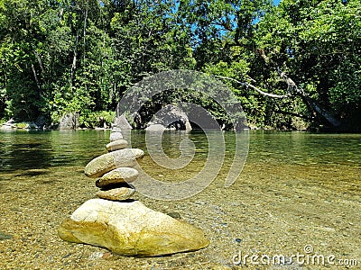 Beautiful view of a tower of rocks in the middle of a pond surrounded by trees Stock Photo