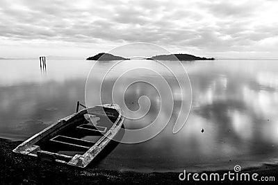 Beautiful view of Trasimeno lake Umbria at dusk, with a little, old boat partially filled by water, perfectly still Stock Photo