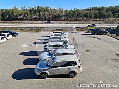Beautiful view of vehicles on parking place on green forest trees and blue sky background. Editorial Stock Photo