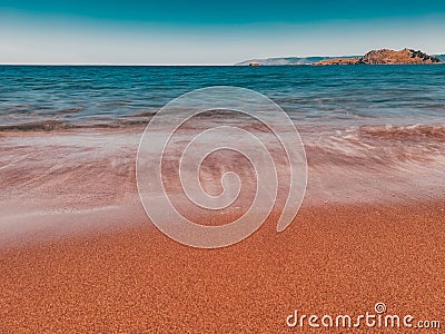 Beautiful view of the waves sweeping off the sand and the mountains in the background Stock Photo