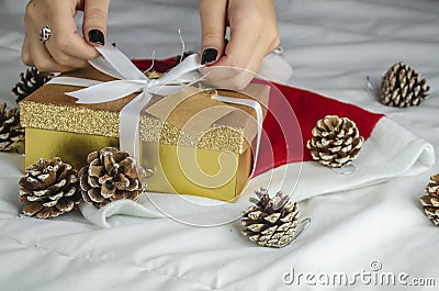 Beautiful view of a yellow box with a glittery golden cover and pine cones on a white bedsheet Stock Photo