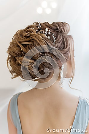 Beautiful volume hairstyle for a bride in a gentle blue light dress with large earrings and adornment in hair Stock Photo