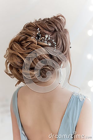 Beautiful volume hairstyle for a bride in a gentle blue light dress with large earrings and adornment in hair Stock Photo