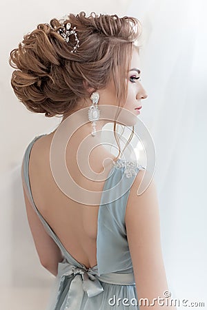 Beautiful volume hairstyle for a bride in a gentle blue light dress with large earrings and adornment in hair Stock Photo