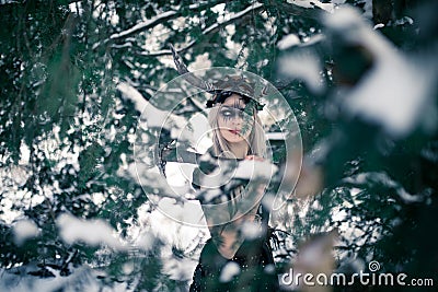 Beautiful warrior woman in image of viking with horned helmet and ax in winter snowy forest Stock Photo