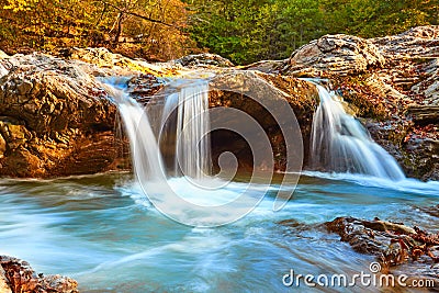 Beautiful waterfall in forest at sunset. Autumn landscape, fallen leaves Stock Photo