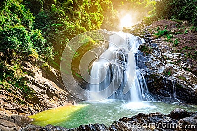 Beautiful waterfall at the mountain with blue sky and white cumulus clouds. Waterfall in tropical green tree forest. Waterfall Stock Photo