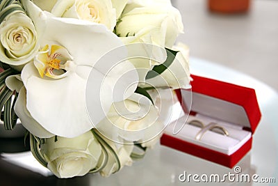 Beautiful wedding bouquet of roses and orchids and red velvet box with gold and platinum wedding rings Stock Photo