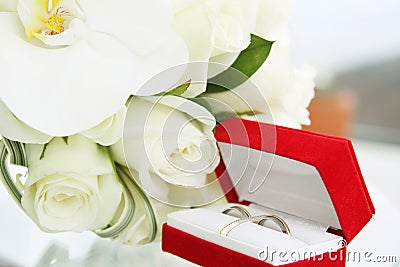 Beautiful wedding bouquet of roses and orchids and red velvet box with gold and platinum wedding rings Stock Photo